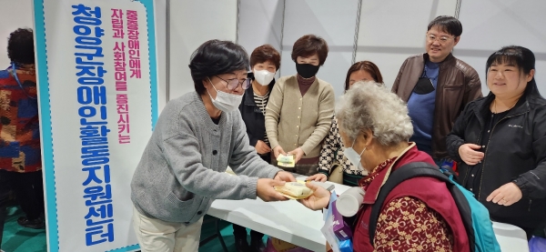 청양군장애인지원센터 문재숙씨가 지역 노인에게 홍보활동을 벌이고 있다.